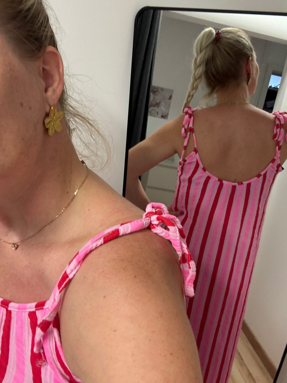 Kleid mit horizontalen Streifen ca. 3-4 cm Dick in pink, rosa und rot abwechselnd.
Der Saum ist dann vertikal in gleicher Farbe gestreift. Spaghettiträger mit knoten Rückansicht im Spiegel
