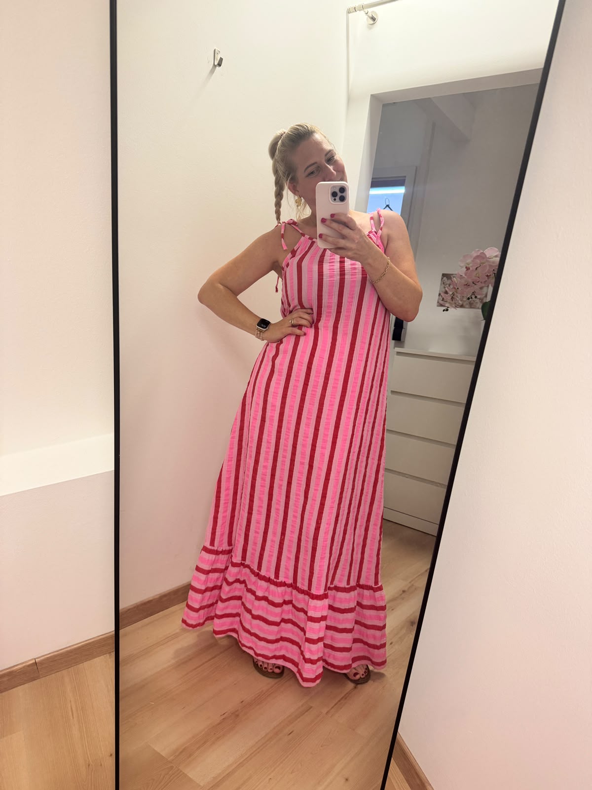 Kleid mit horizontalen Streifen ca. 3-4 cm Dick in pink, rosa und rot abwechselnd.
Der Saum ist dann vertikal in gleicher Farbe gestreift. Spaghettiträger mit knoten